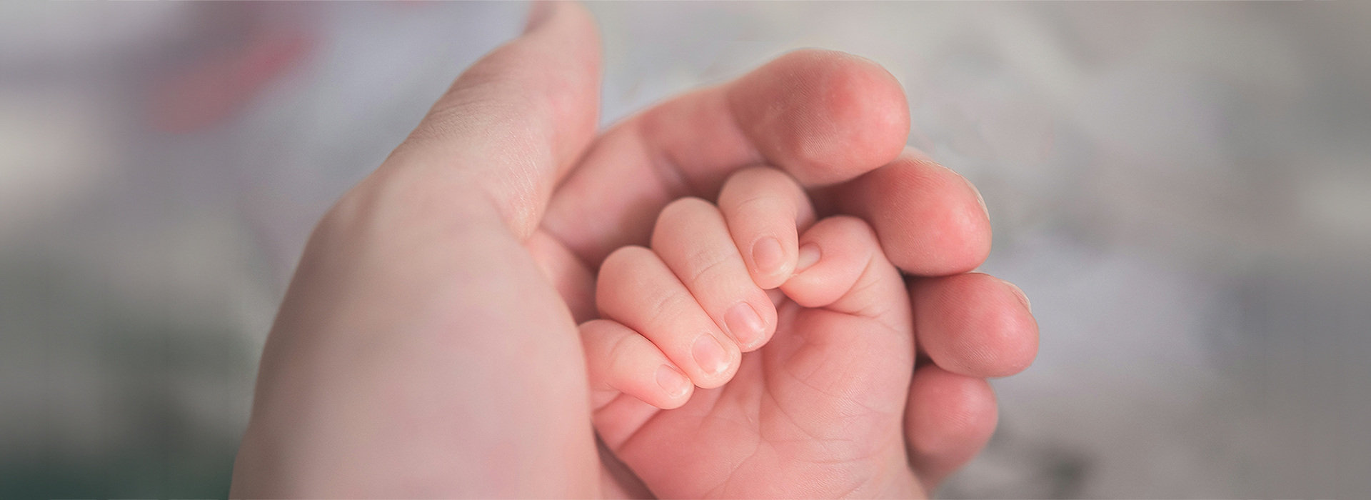 Adult hand holding baby hand